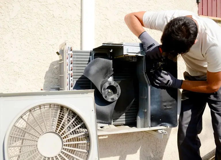 A man working on an air conditioner outside.