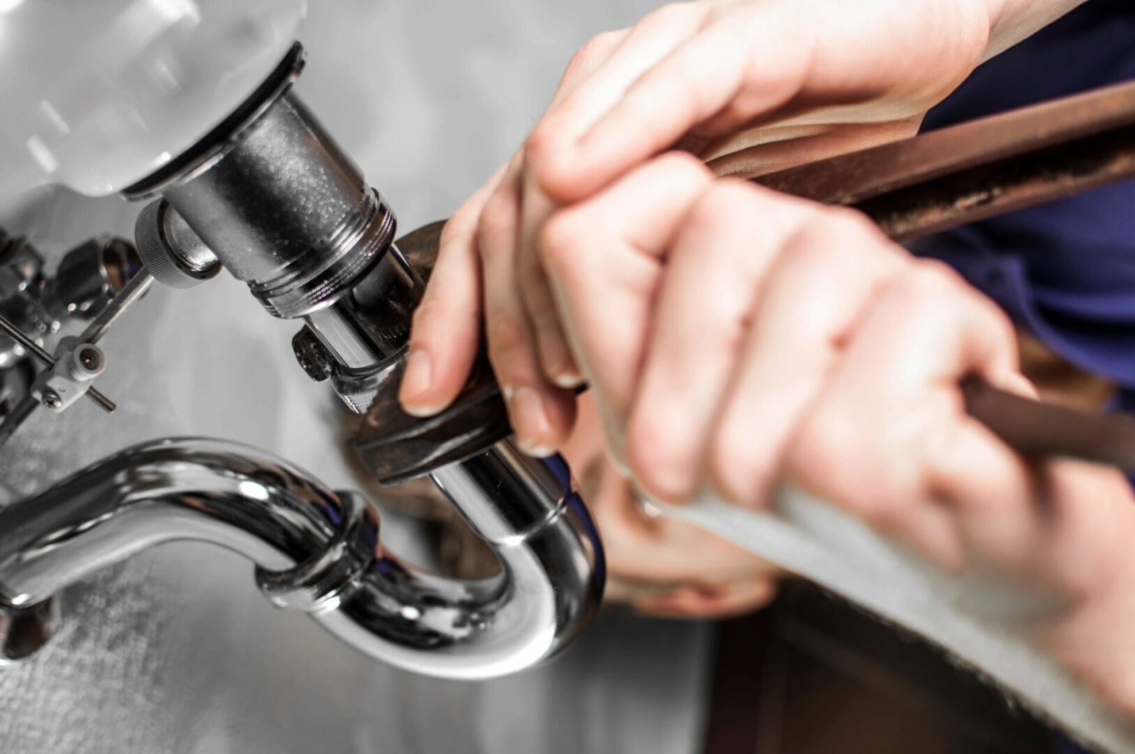 A person is fixing the faucet of a sink.